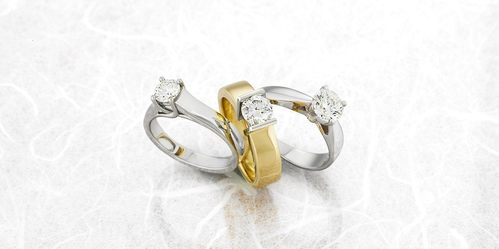 Three Engagement Rings on Reflective Surface